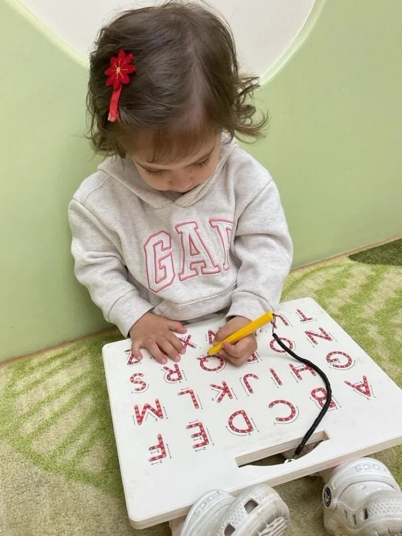 A child tracing letters on an alphabet board