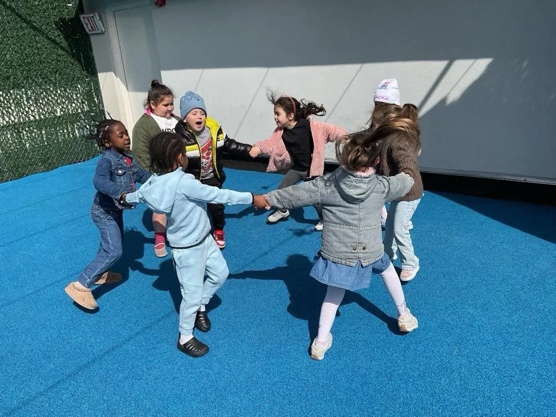 Children dancing in a circle on the rooftop playground