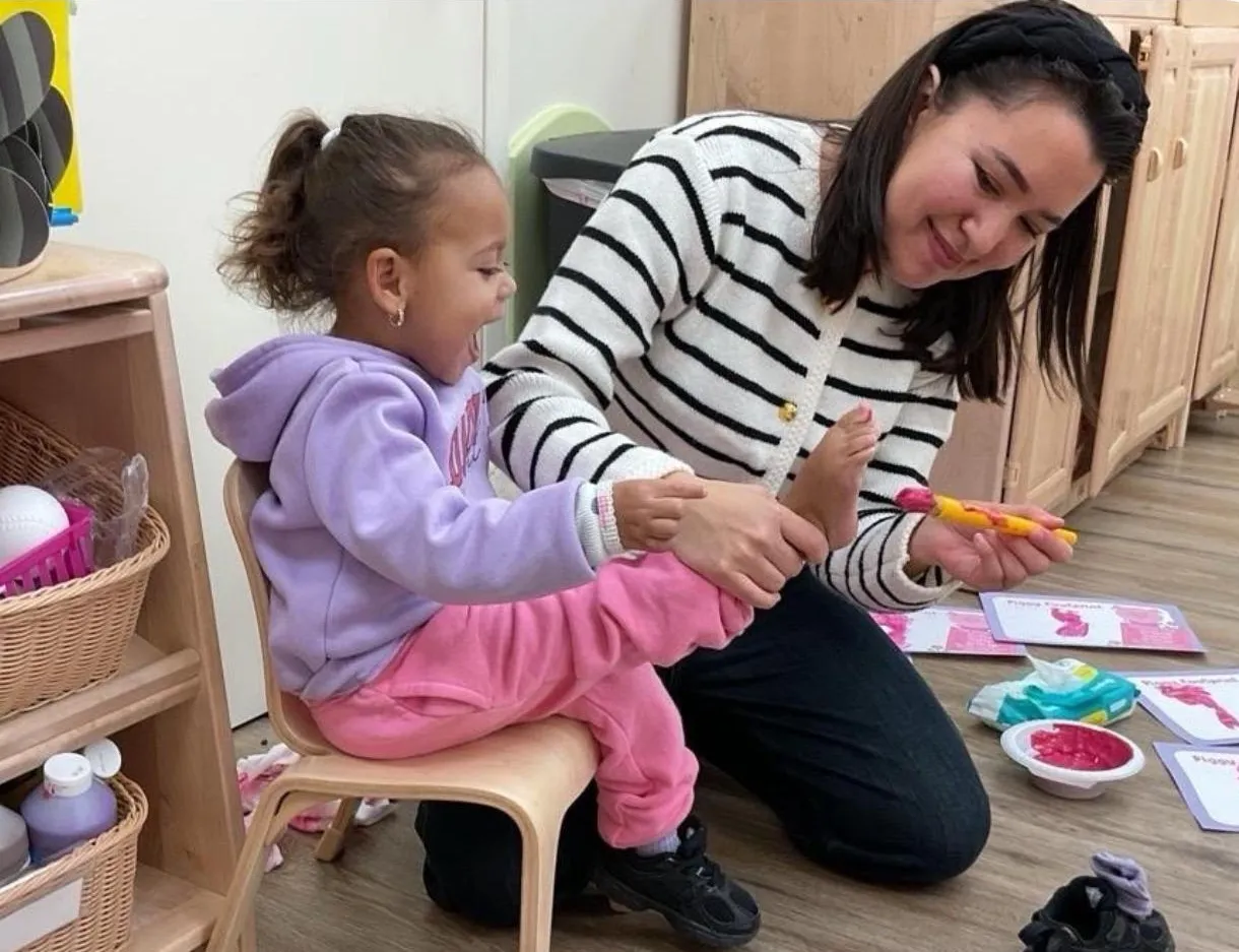 An educator kneeling beside a little girl during a classroom activity