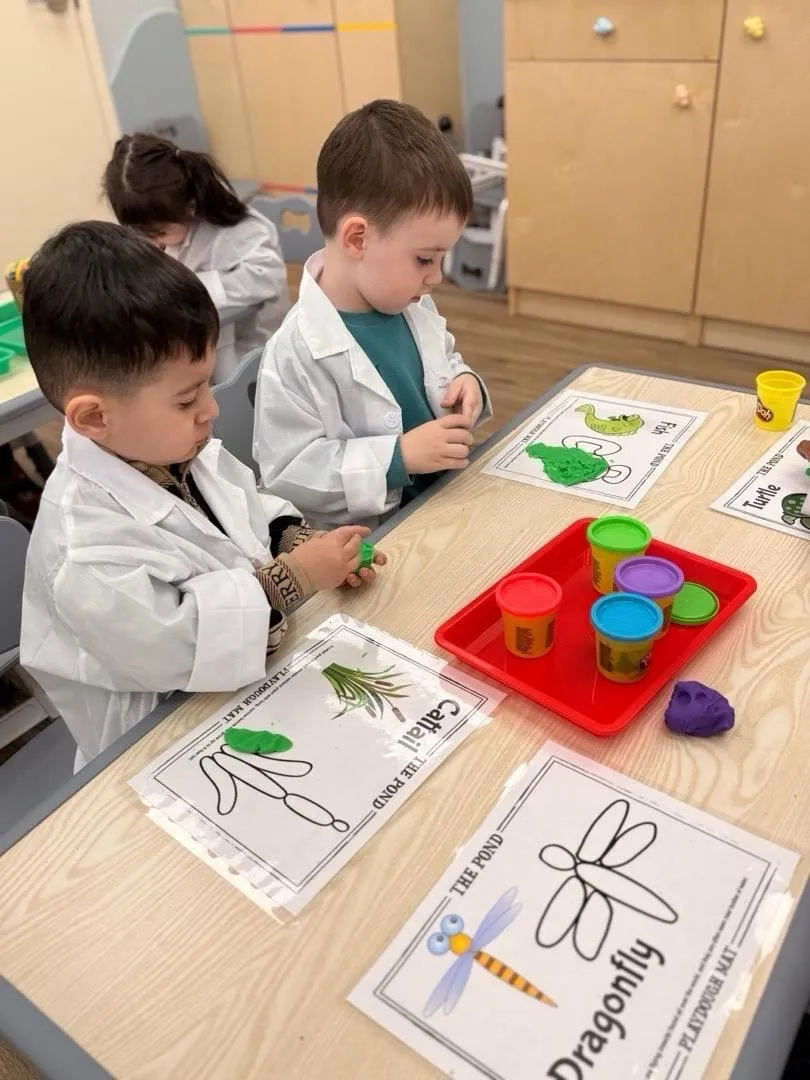 Children in lab coats building insects out of play dough